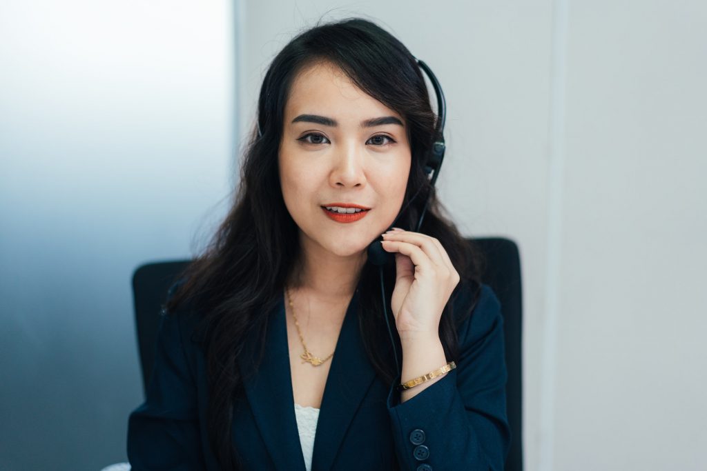 Portrait of Asian female telemarketer talking to customer